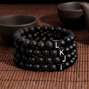 Macro detail of lava stone and onyx bracelets with square initial letter beads