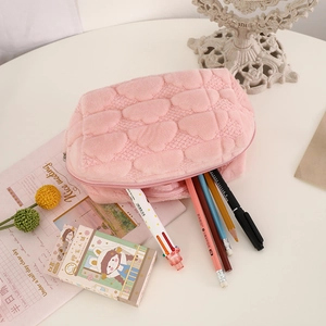 Detail view of pink cloud-textured cosmetic bag with plush heart patterns and zipper