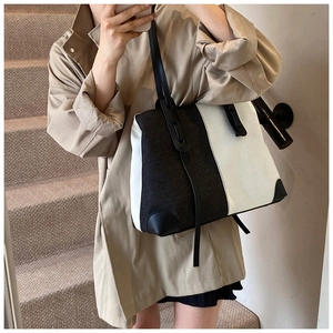 Close-up of contrast denim tote bag with black leather straps and reinforced corners