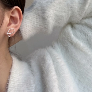 Close-up of a silver wing-shaped hollow line earring worn on the ear for a stylish look