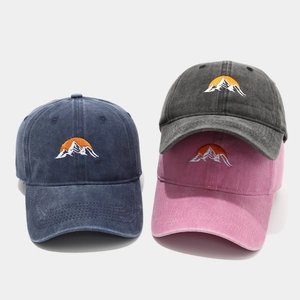 Detail of embroidered mountain sunrise pattern on washed cotton baseball caps