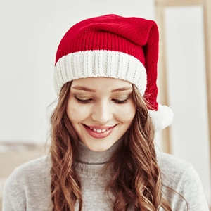 Close-up of red and white knit Christmas hat with soft white pompom on a female model