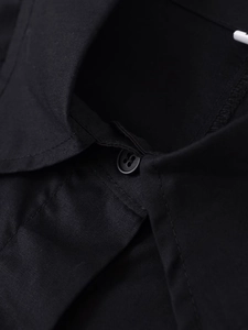 Close-up of matte black button and refined cotton fabric texture on casual utility shirt