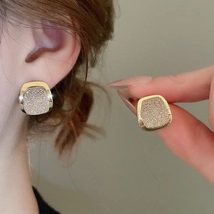 Detailed close-up of 18k gold plated square stud earrings with champagne glitter inlay