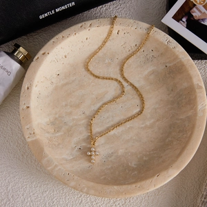 Détail d'un collier en acier titane doré avec un pendentif en forme de croix de perles