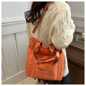 Rear view of model wearing orange nylon tote bag with adjustable strap for versatile styling