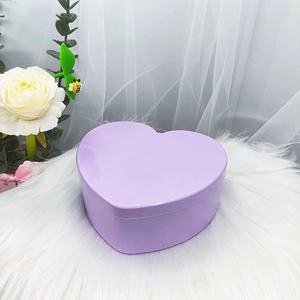 Vista macro de una caja de regalo de hojalata lila con forma de corazón sobre felpa
