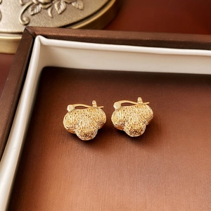 Macro shot of gold knot earrings with brushed metal texture in a luxury gift box