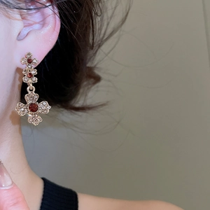 Close-up of vintage flower earrings with red and white crystals on a female model