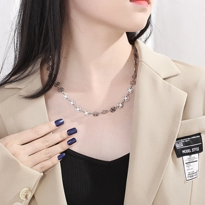 Unique stainless steel necklace with coin cross pattern on neck of a model