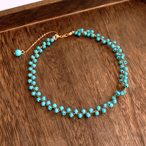 Vue détaillée macro de perles turquoises facettées et fermoir mousqueton doré sur plateau