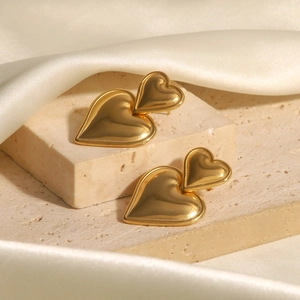 Minimalist 18k gold plated double heart stud earrings displayed on elegant white silk