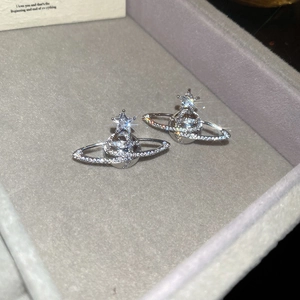 Detailed view of silver zircon Saturn earrings resting in a gray velvet jewelry box