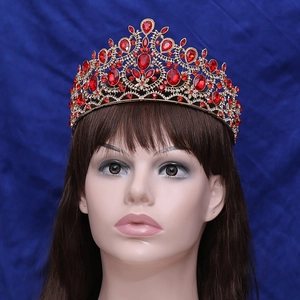 Close-up of ornate gold bridal crown with red crystals and rhinestones on a mannequin