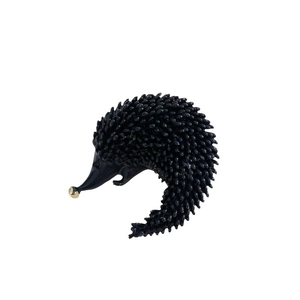 Cute black hedgehog brooch with golden nose and detailed texture on white background