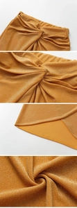 Detail of metallic gold wrap skirt featuring twisted waist and shimmering fabric texture