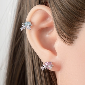 Bow heart stud earrings set with blue and pink gemstones on a model's ear