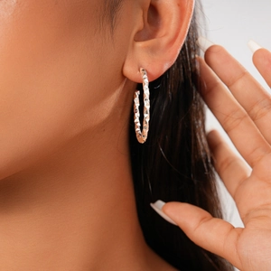 Macro shot of silver C-shaped hoop earrings with geometric diamond-cut textures