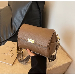 Gros plan du sac bandoulière marron en cuir litchi avec large sangle style ethnique