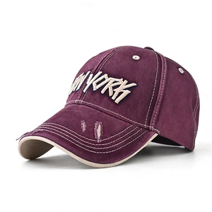 Detail of burgundy canvas baseball cap with white NEW YORK embroidery and distressed brim