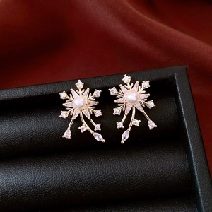 Vue macro détaillée de boucles d'oreilles fleur bicolore or avec perles et cristaux en boîte