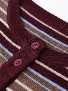 Close-up of multicolor striped knit cardigan with wine red resin buttons and fine texture