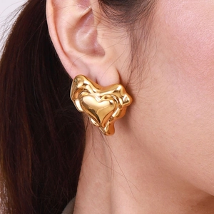 Lava textured gold heart stud earrings in stainless steel worn by a model