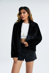 Détail de la texture en fausse fourrure noire sur une veste cintrée à manches longues