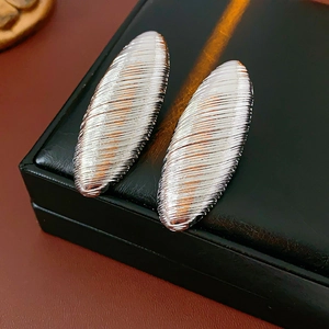 Detailed shot of silver textured oval hoop earrings on a black leather jewelry box