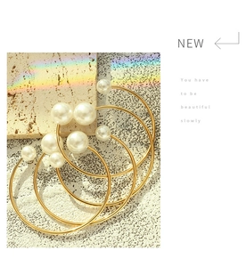 Detail of elegant gold-plated layered cuff bracelet with round white pearls and rainbow light