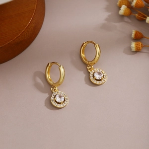 Detailed macro shot of golden drop earrings with sparkling circular zircon inlay
