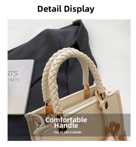 Detail of cream leather bucket bag with braided rope handles and heart-shaped pendant