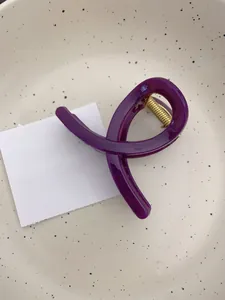 Détail d'une pince à cheveux violet foncé avec mécanisme à ressort doré sur plateau