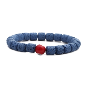 Nahaufnahme blauer Lavasteinperlen und einer roten Augenperle an einem neutralen Armband