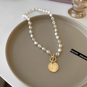 Detail view of baroque pearl necklace with a vintage gold coin pendant and T-bar toggle clasp