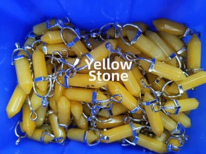 Bulk yellow crystal hexagonal pillar pendants stacked in a blue tray for wholesale