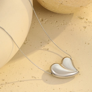 Close-up of minimalist silver heart pendant on a delicate snake chain necklace