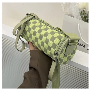 Detail of checkered barrel crossbody bag with wide strap and textured fabric texture