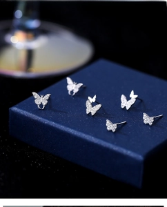 Macro shot of S999 sterling silver butterfly stud earrings set on blue jewelry box