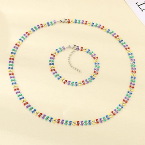 Detailed view of colorful wheat leaf necklace and bracelet set on beige fabric