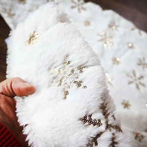 Detail of white faux rabbit fur Christmas tree skirt with gold sequin snowflakes