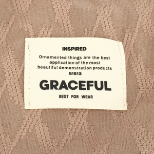 Detail of light brown knit beanie showing wavy texture and white woven label with text