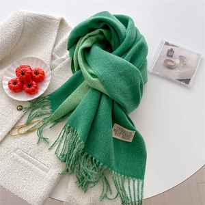 Detailed shot of green knitted scarf texture with fringe and branded woven label