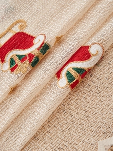 Detailed embroidery of Santa hats and gift bags on cream mesh fabric for Christmas decor