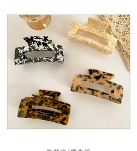 Detail view of four acetate hair claws in marble and tortoiseshell patterns with metal springs