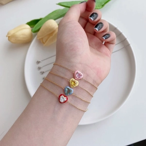 Close-up of four S925 silver gold-plated bracelets with colorful enamel heart charms