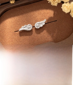 Close-up of silver angel wing ear studs made of titanium steel with size specifications