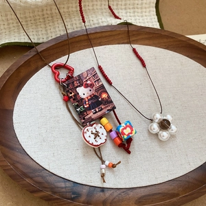 Handmade resin cat and apple pendant necklace with colorful beads on a brown cord