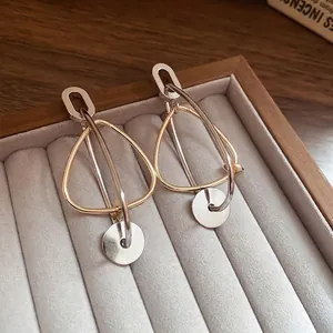 Boucles d'oreilles géométriques en or et argent sur présentoir en velours