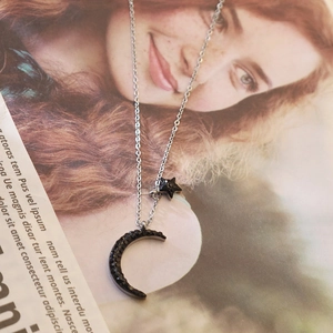 Close-up of star and moon charms with black crystals on a stainless steel necklace